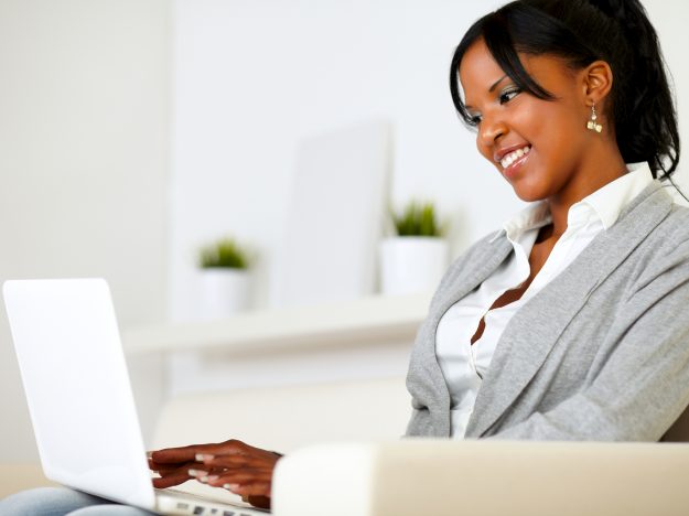 Portrait of an afro-american young woman using laptop at home indoor